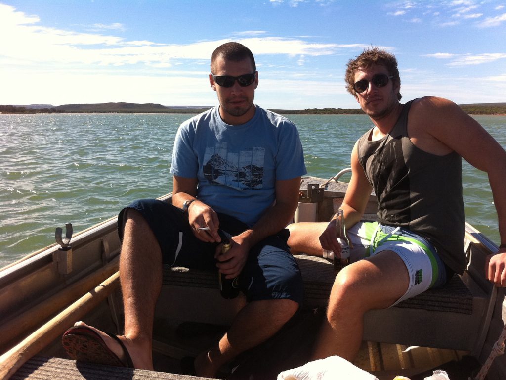 Two guys taking a rest from paddling the boat to the national park in West Coast, Australia. Hitting a cow on the west coast road trip