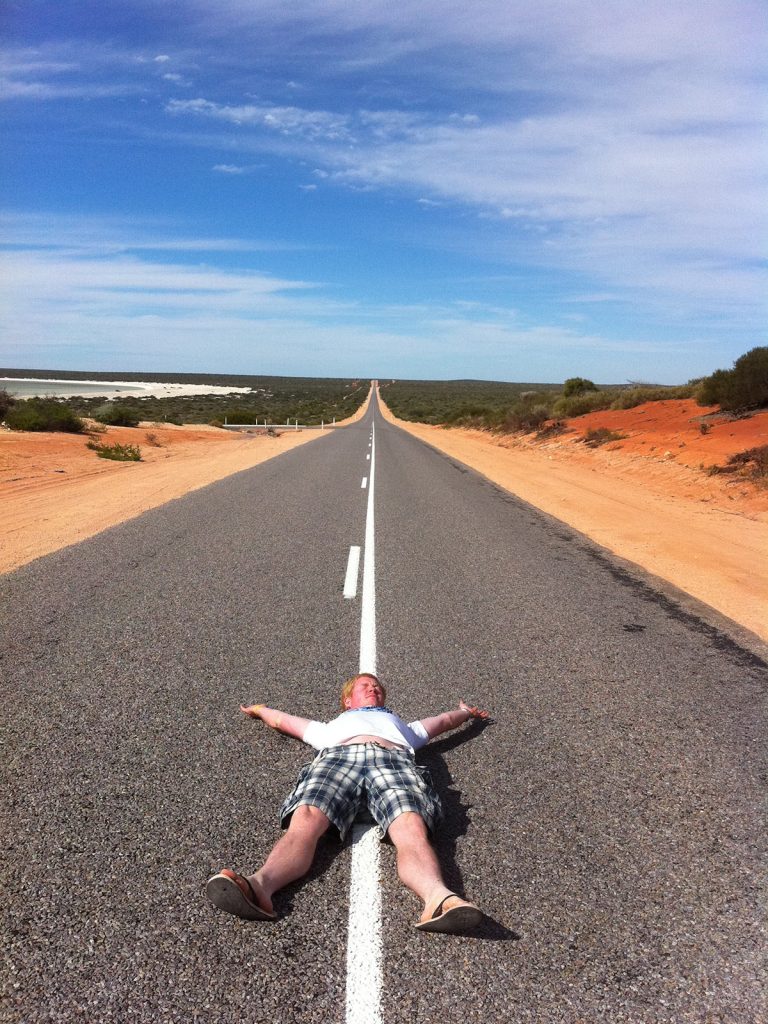 Guy lying in the middle of the road in West Coast, Australia. Hitting a cow on the west coast road trip