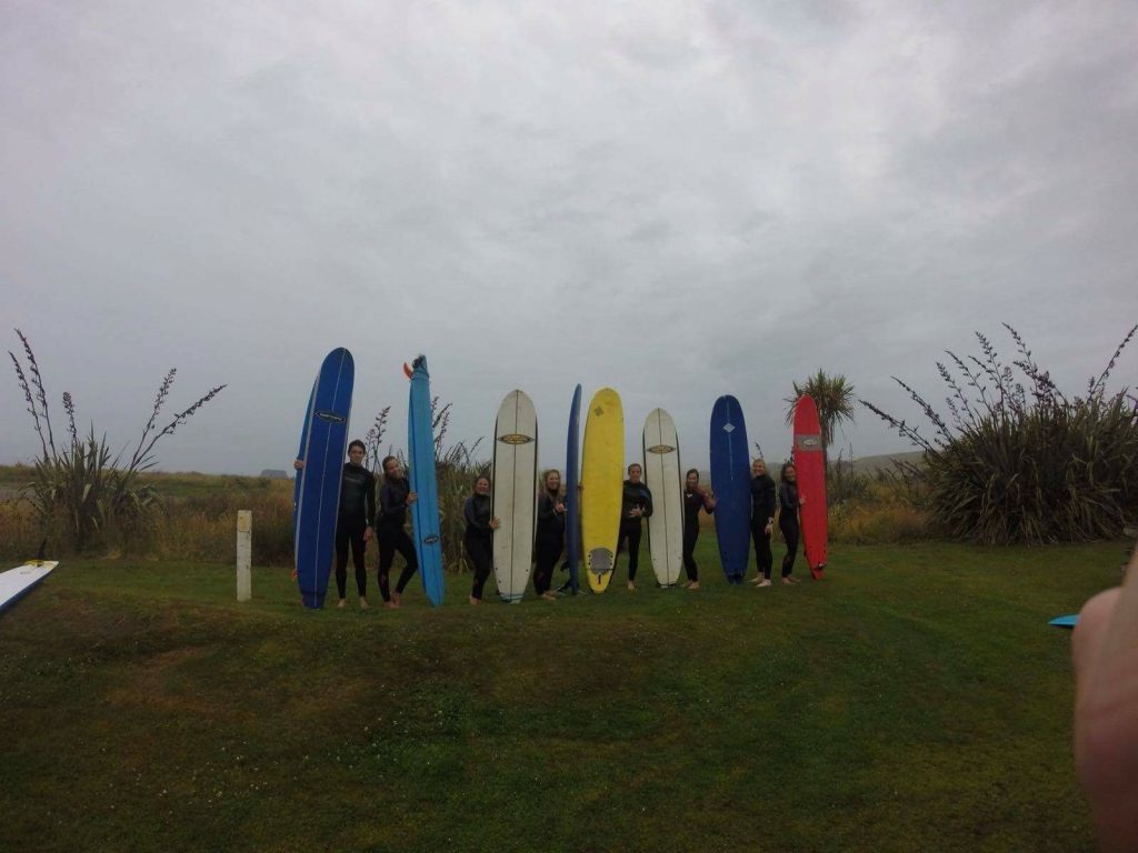 David Simpson and friends wearing wetsuits and holding surfboards in WestPoint, New Zealand. The Poo Pub