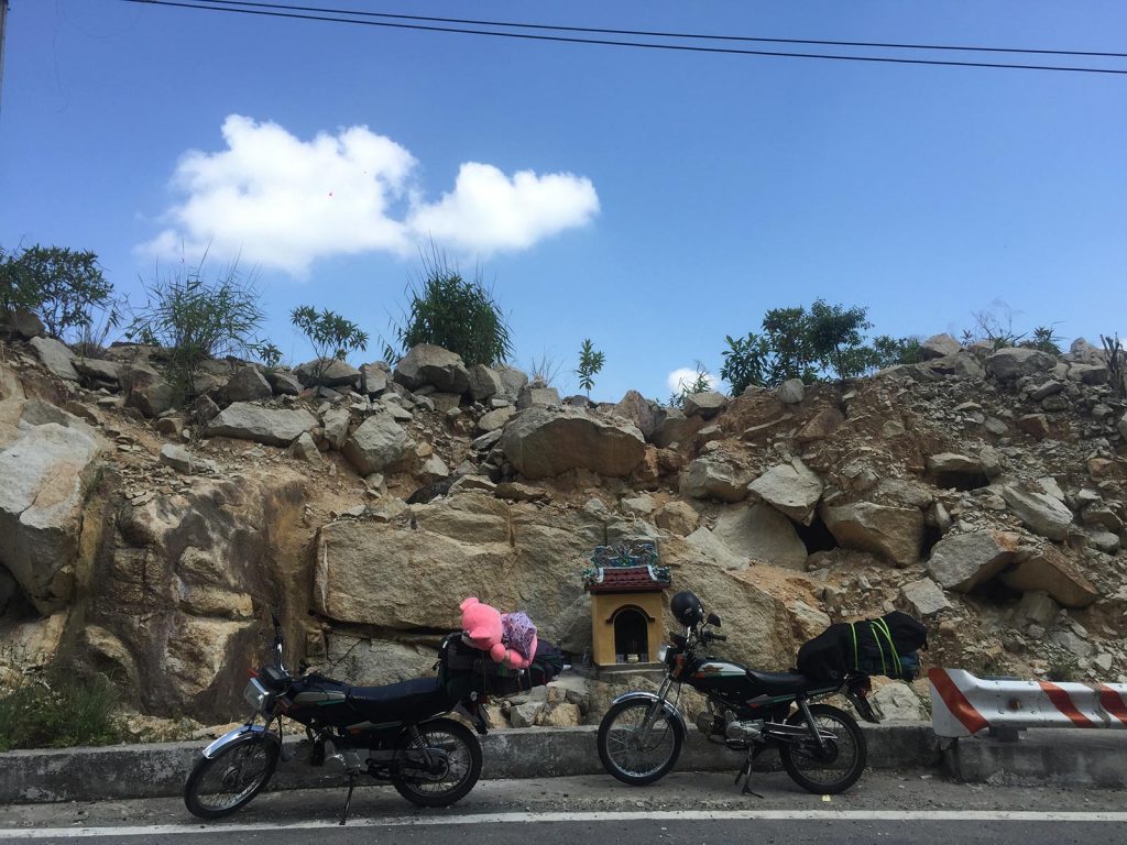 Two motorbikes by the road at a rocky hillside in Da Lat, Vietnam. Night rider and a broken bike
