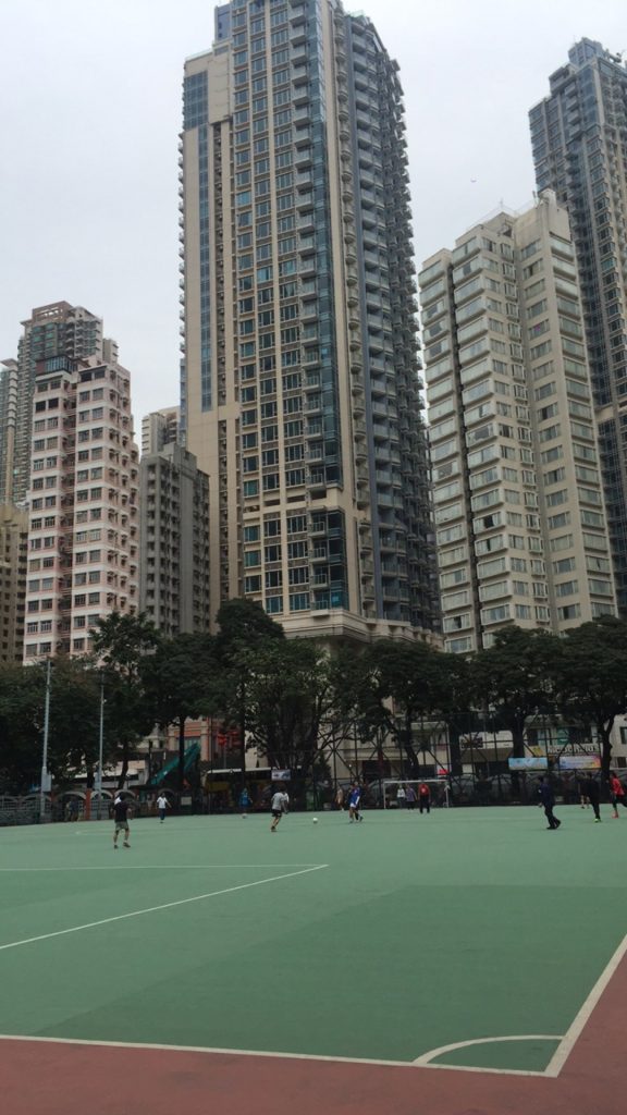 Football court surrounded by tall buildings in HK. The return of my luggage in Hong Kong