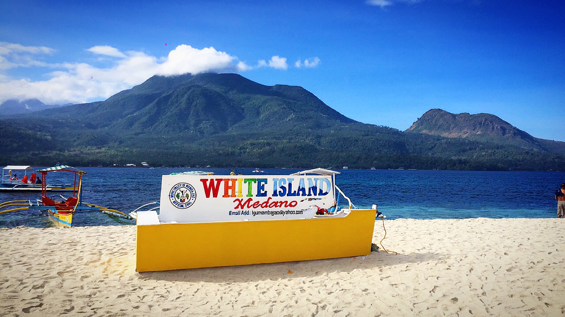 White Island sign with mountains and sea backdrop in Camiguin, Philippines. White Island on Camiguin