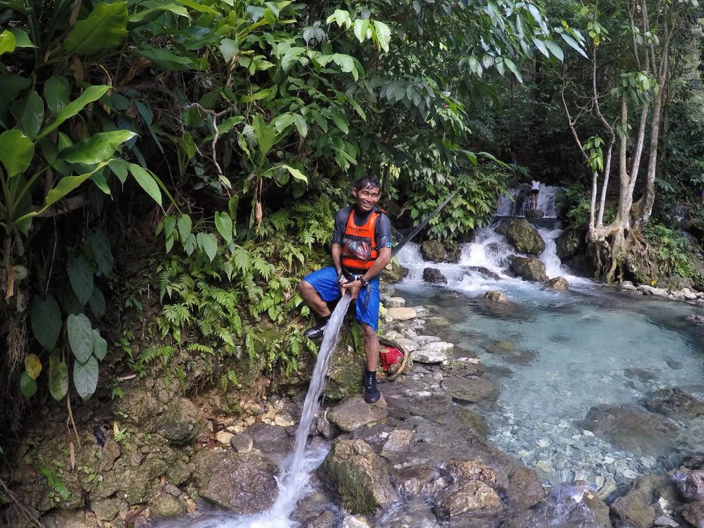A local guide hosing water to the river in Moalboal, Philippines. Canyoneering in Moalboal