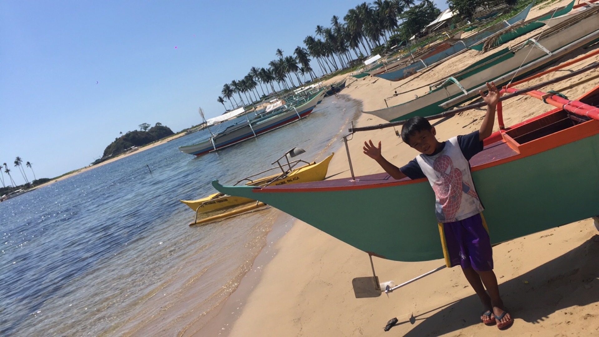 A local kid by the fishing boats by the beach in Nacpan, Philippines. The best beach in the world all to myself