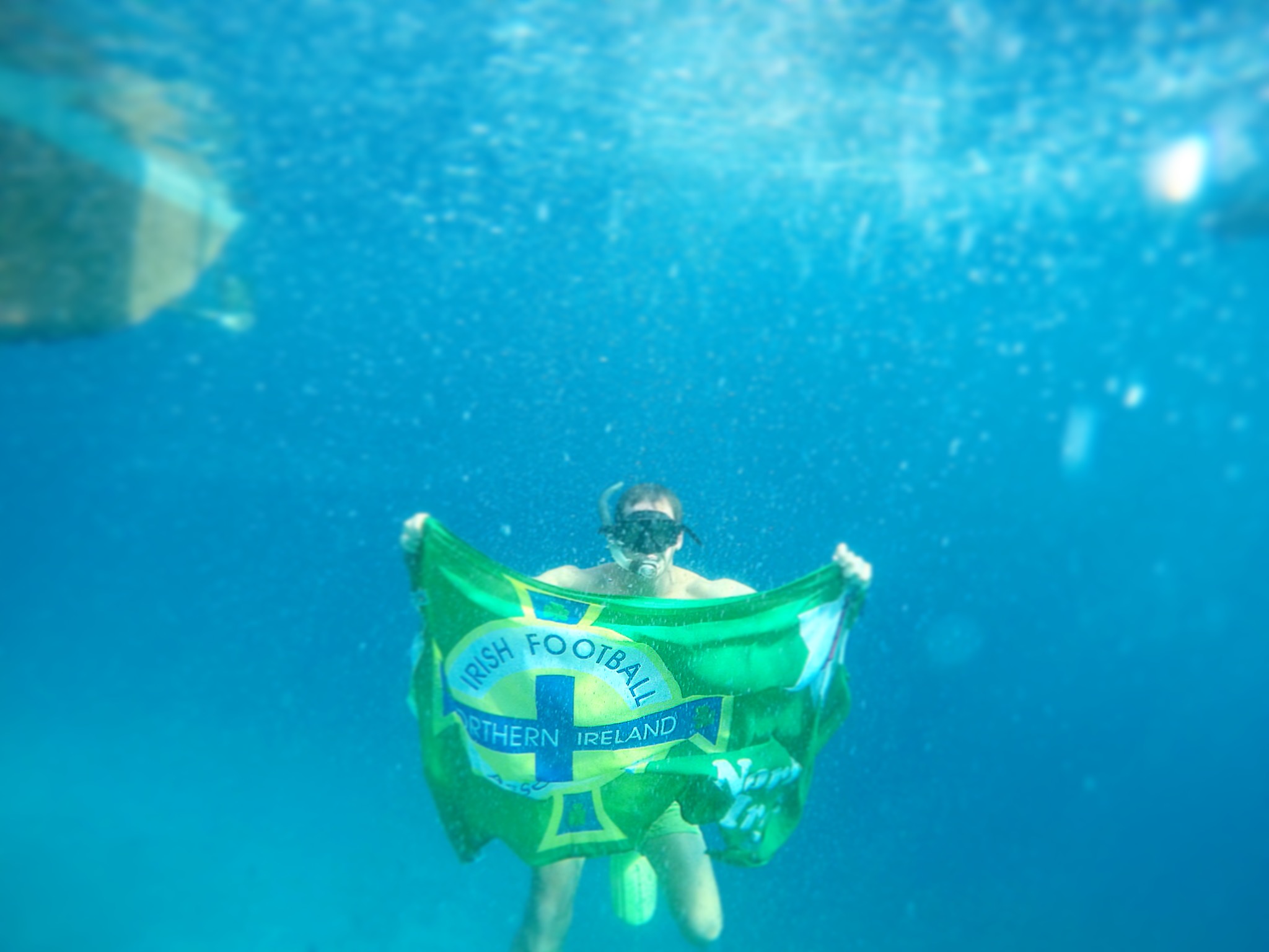 David Simpson holding the NI flag underwater in Nacpan, Philippines. The best beach in the world all to myself