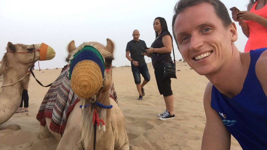 David Simpson with camel at desert in Dubai, UAE. Safaris in Dubai & waffles in Brussels