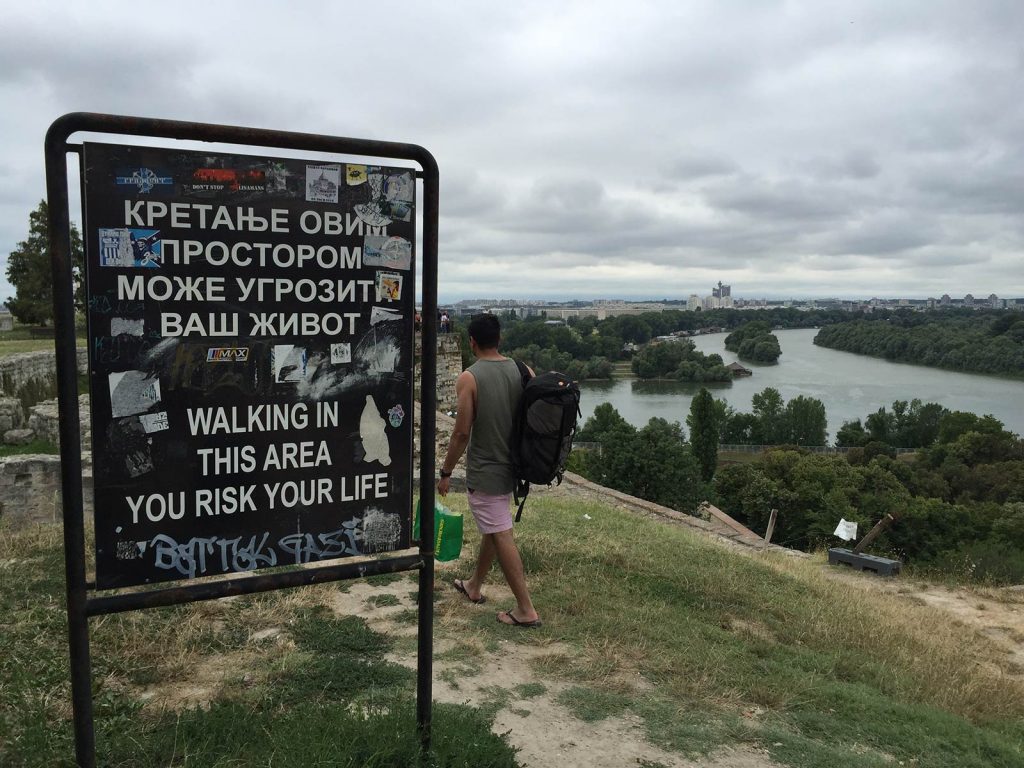 Man walking along warning sign in Belgrade, Serbia. My Balkans trip summed up in photos