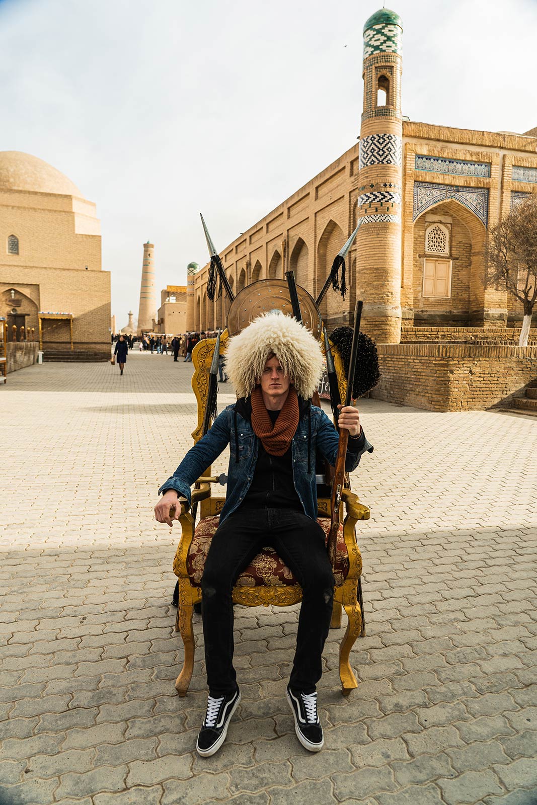 David Simpson wearing a fur hat and seated in the middle of the street in Khiva, Uzbekistan. Crossing in Uzbekistan and the train to Bukhara