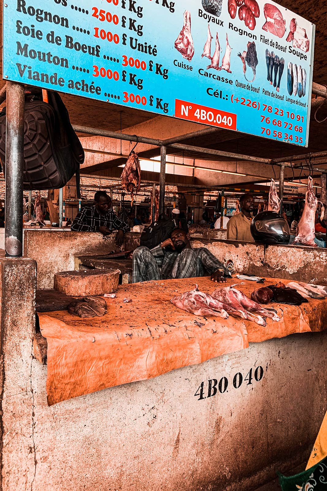 Butcher asleep in his stall at market in Ouagadougou, Burkina Faso. The most horrible zoo