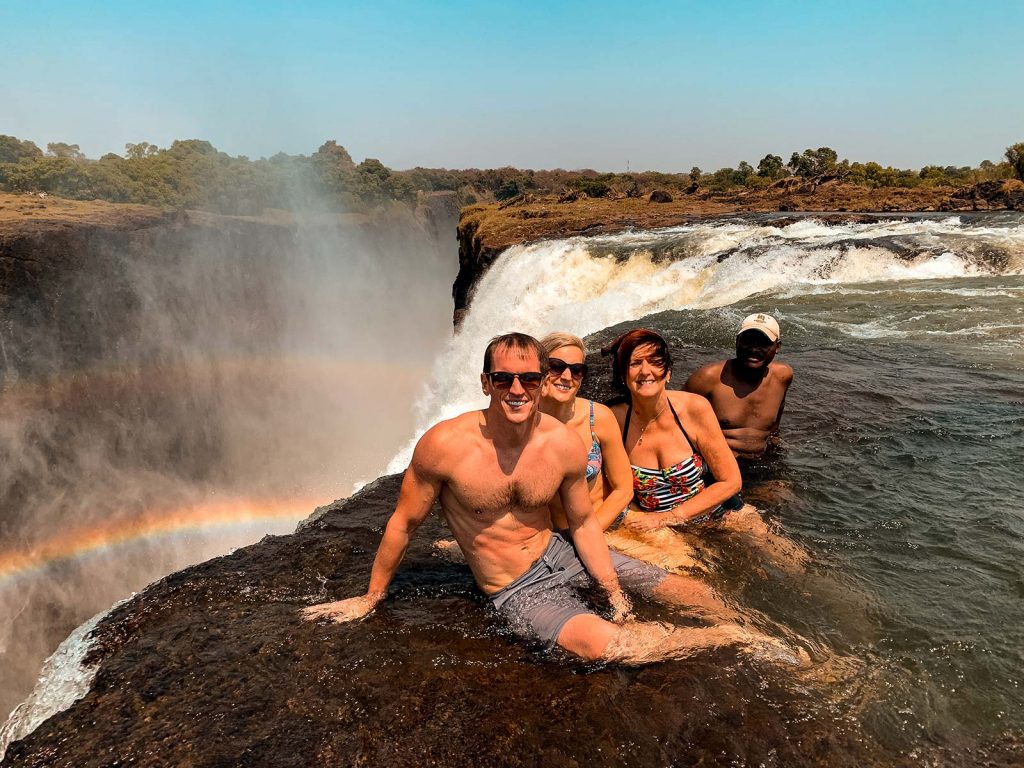 David Simpson and family with local guy at Devil's Pool at Victoria Falls in Zambia, Africa. The Southern Africa series reflection post