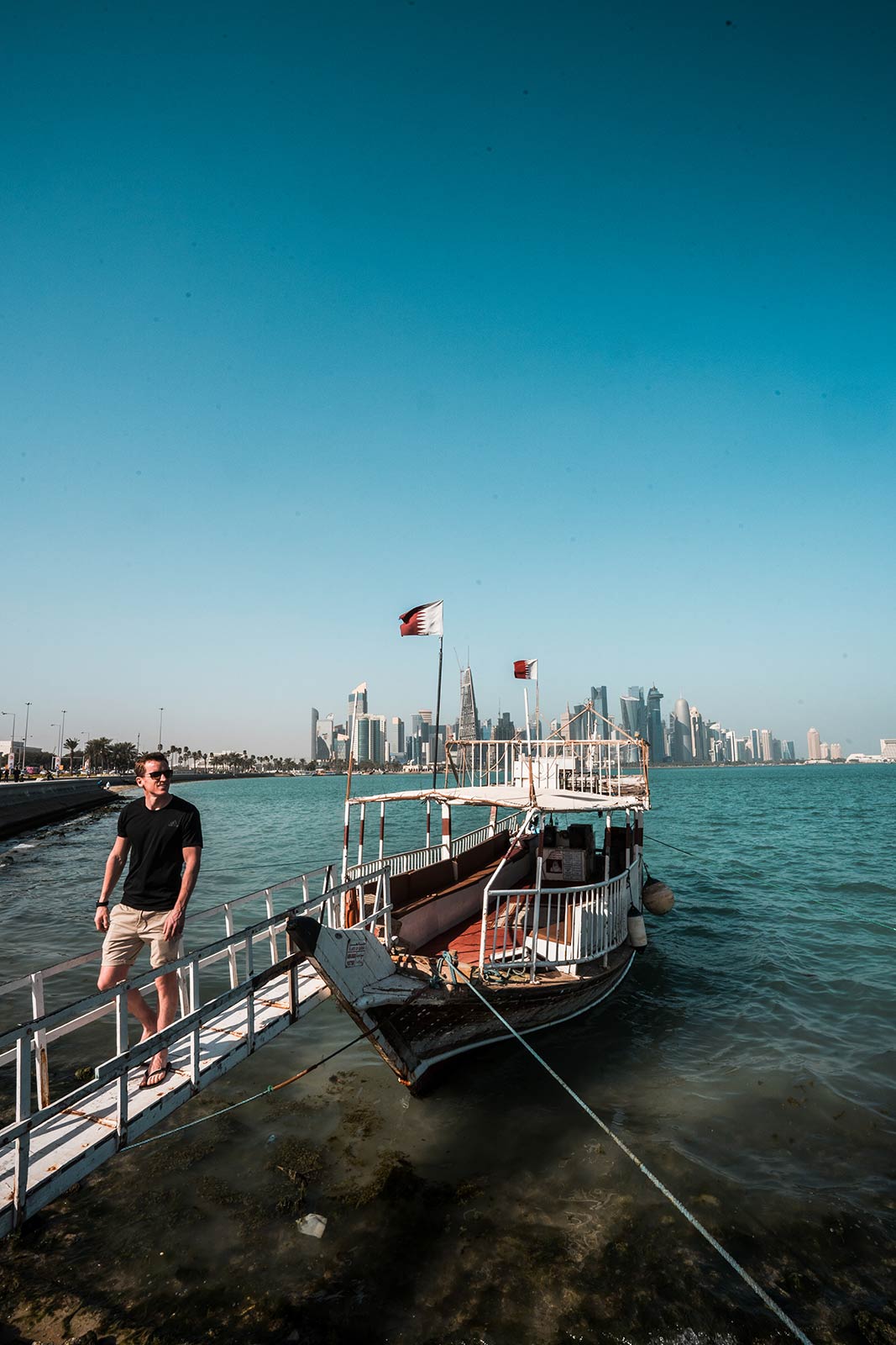 David Simpson and traditional dhow wooden boat at Corniche Marina in Doha, Qatar. Swimming in Doha Airport