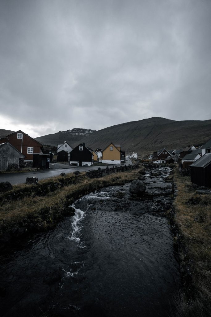 Houses by the creek at Gjogv in Faroe Islands. Getting blown off Mt Villingardalsfjall