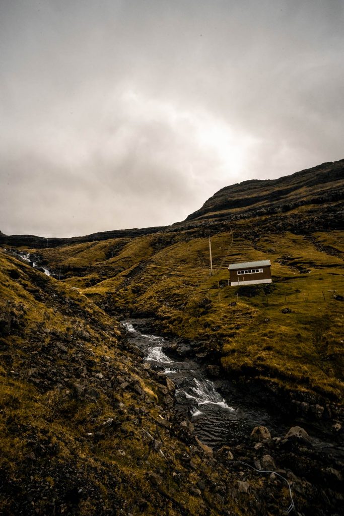 House at the mountainside in Faroe Islands. Getting blown off Mt Villingardalsfjall