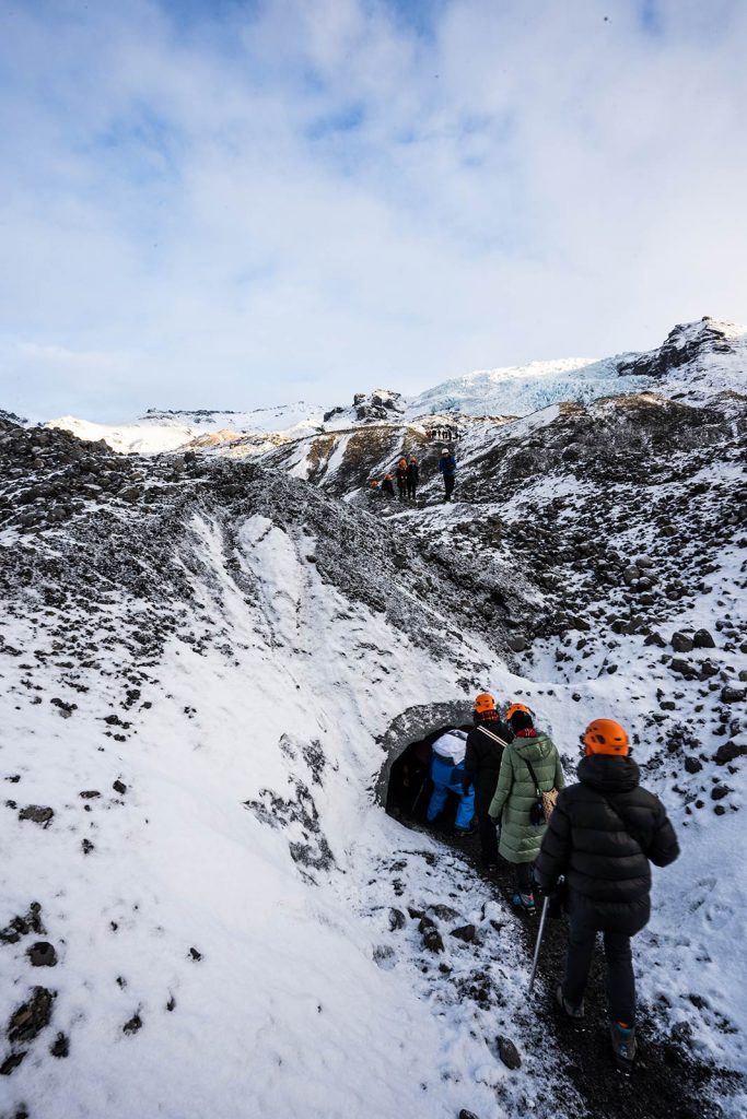 Tourists entering cave at Skaftafellsjokul glacier in Iceland. Ice caving in Iceland