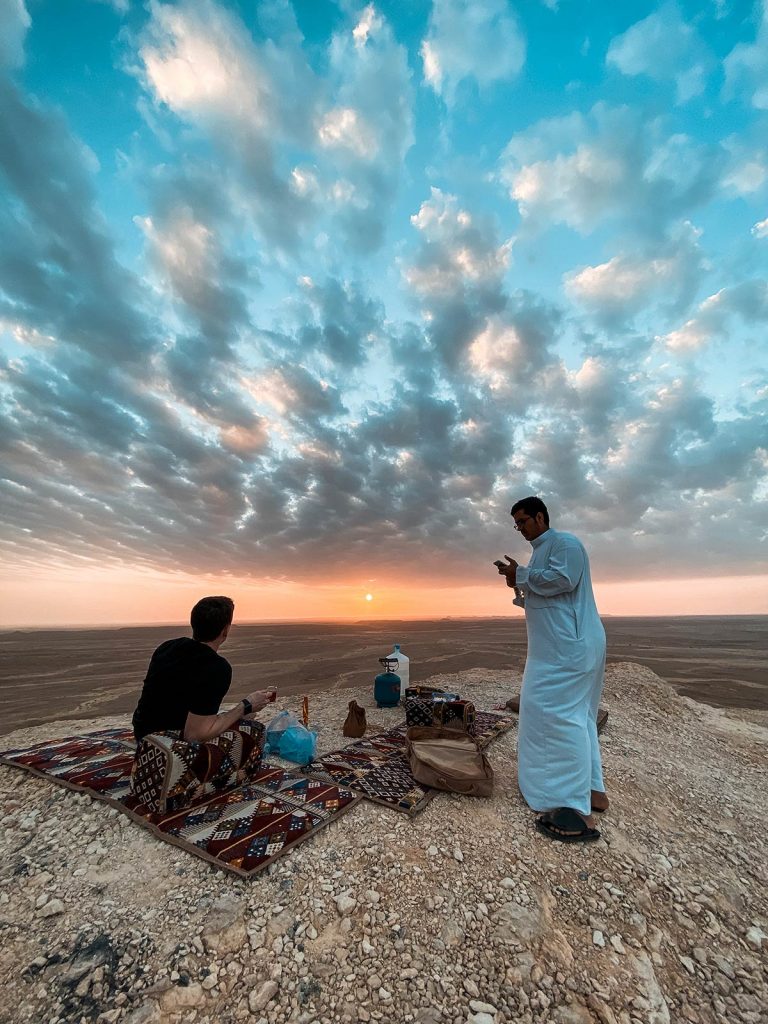 David Simpson drinking tea with local guy during sunset at amphitheater in Saudi Arabia. A trip to the edge of the world