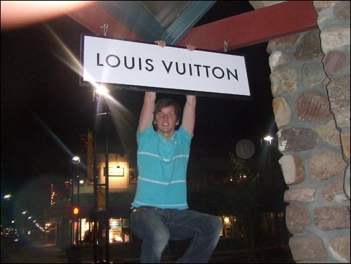 David Simpson hanging on Louis Vuitton sign in Banff. Three weeks in Banff