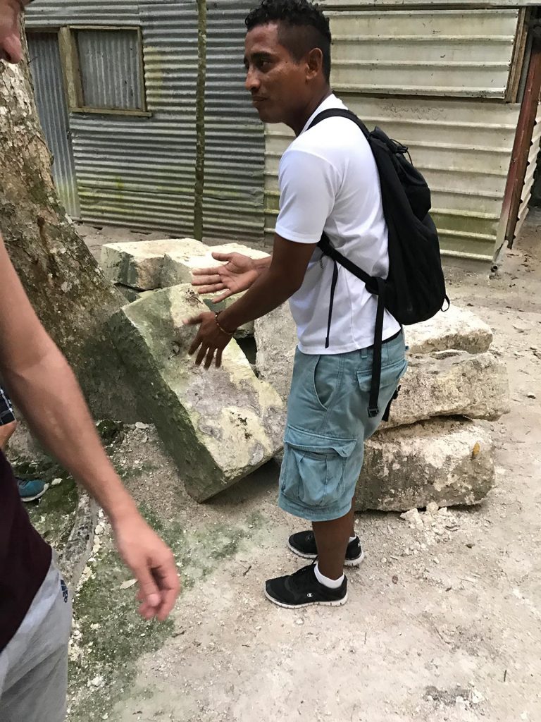 A local guide near stone blocks in Tikal, Guatemala. A dislocated shoulder & Tikal Ruins