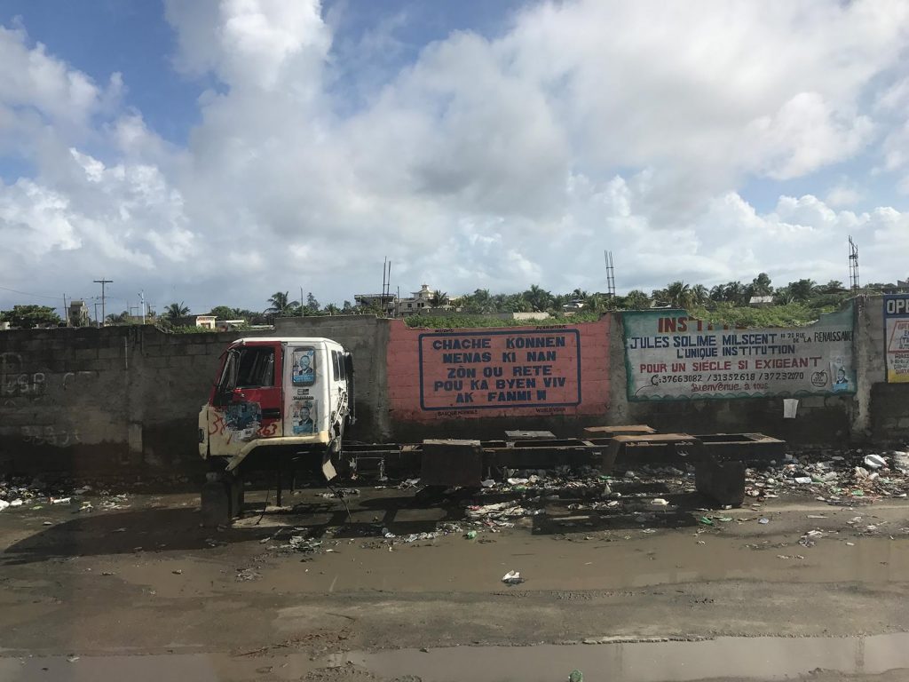 Truck at the roadside with no wheels along garbage heap in Haiti. Haiti & Dominican Republic, an Island of two halves