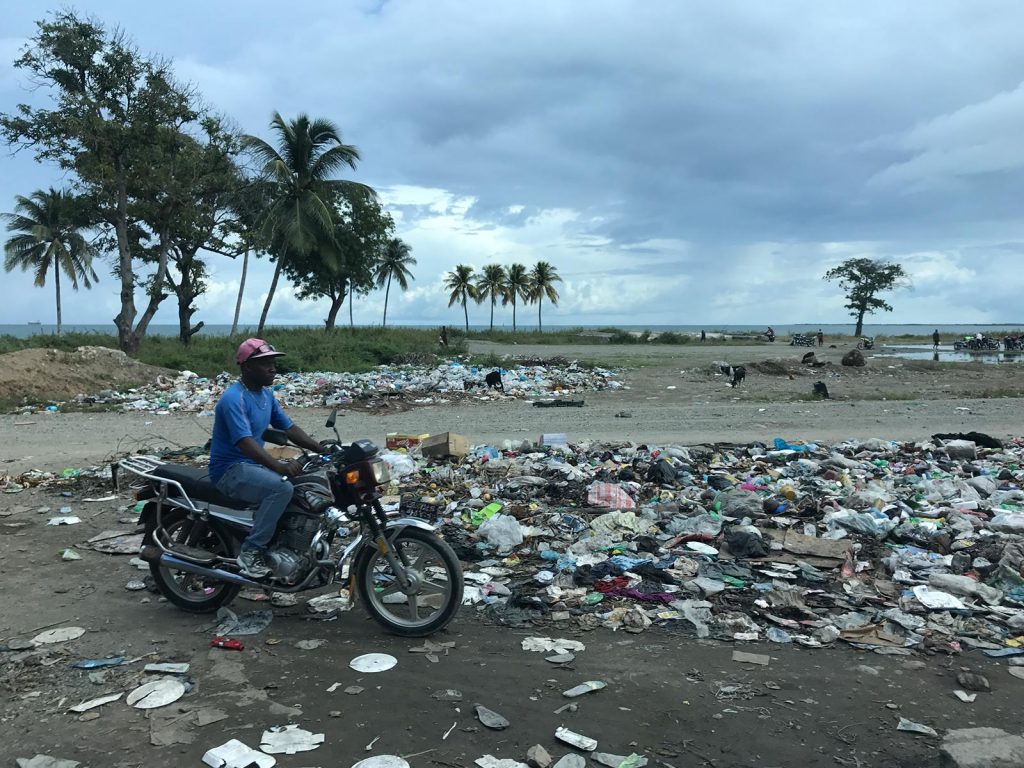 Motorcycle rider passing by garbage heap in Haiti. Haiti & Dominican Republic, an Island of two halves