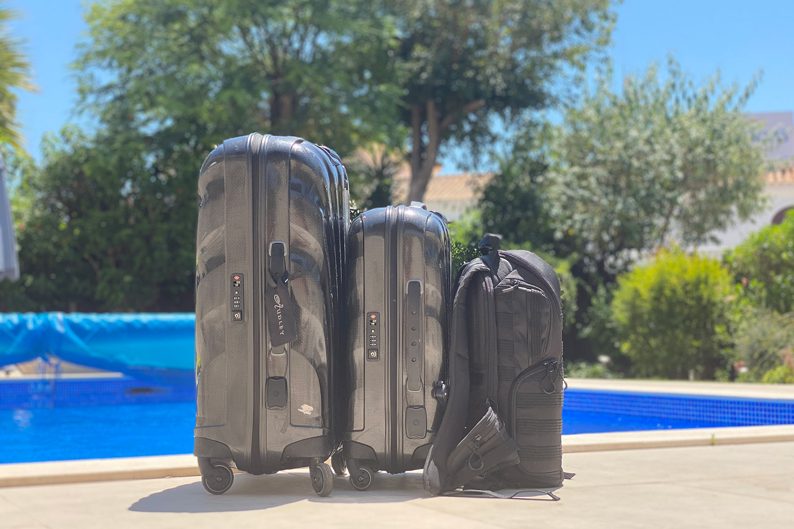 Two suitcases and a backpack in front of a swimming pool. The best backpack for travelling