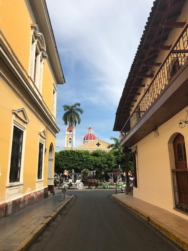 Street with horse-drawn carriages and a church in Leon, Nicaragua. Volcano boarding in Leon, Nicaragua & full guide