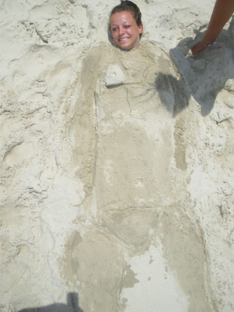 A girl buried in sand in Byron Bay. The Zoo, Brissie & Byron Bay