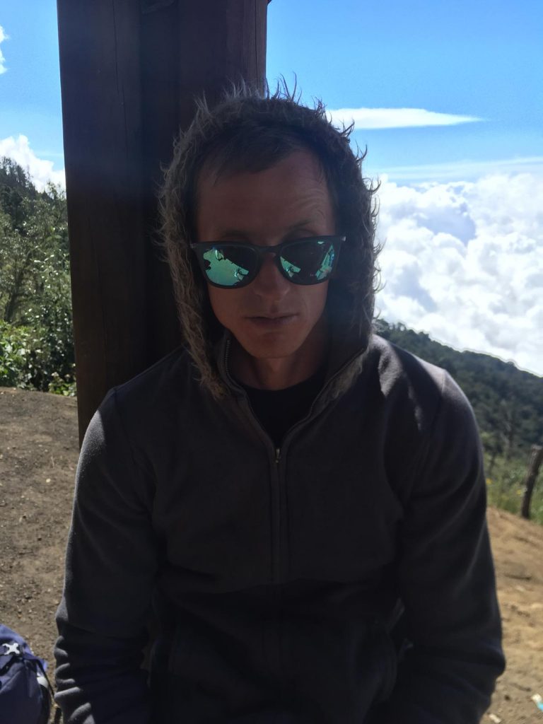 David Simpson wearing a hoodie and dark glasses while climbing a volcano in Antigua, Guatemala. Volcano hiking in Guatemala