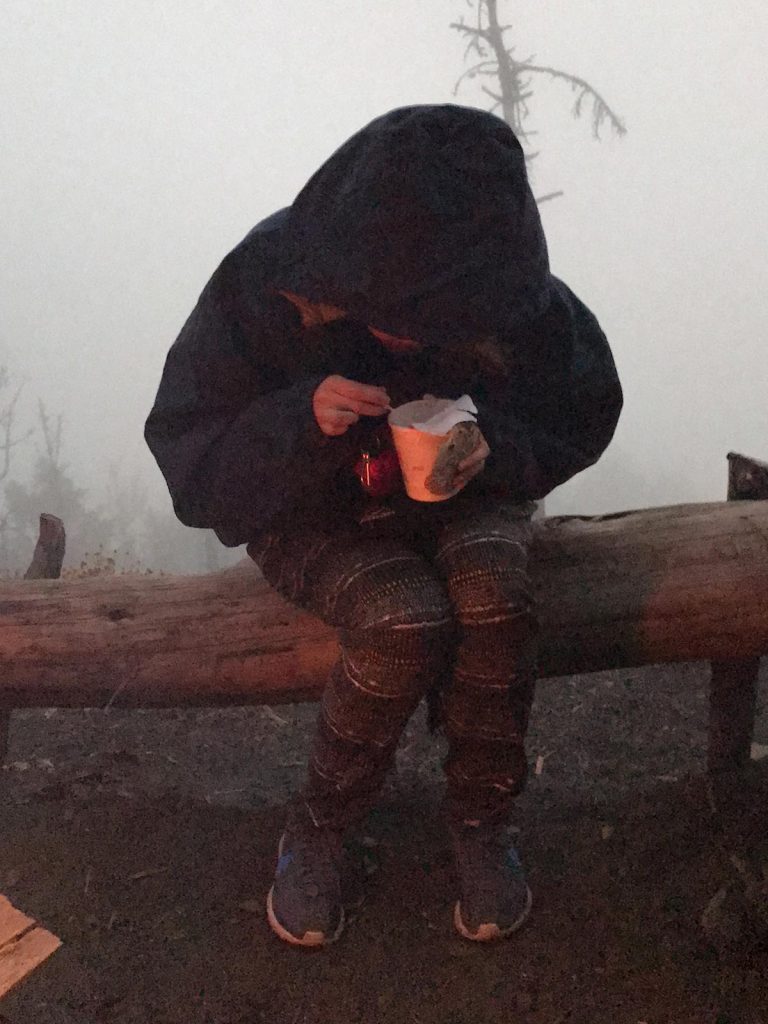Friend girl seated and eating noodles at camp in Antigua, Guatemala. Volcano hiking in Guatemala