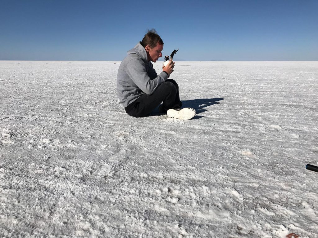 David Simpson holding cup with two friends inside in Uyuni Salt Flat, Bolivia. Atacama desert & Bolivian salt flats road trip & full guide