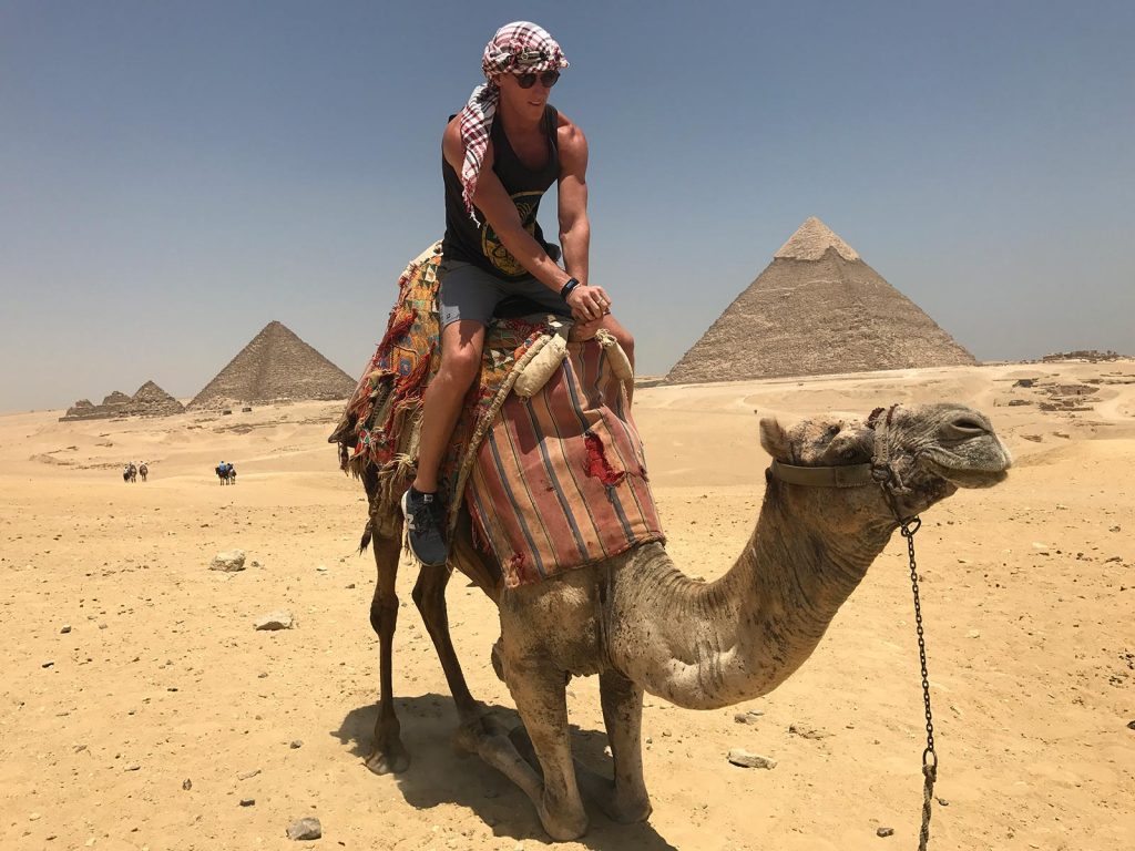 David Simpson riding kneeling camel in Cairo, Egypt. Getting inside the Ancient Pyramids of Giza