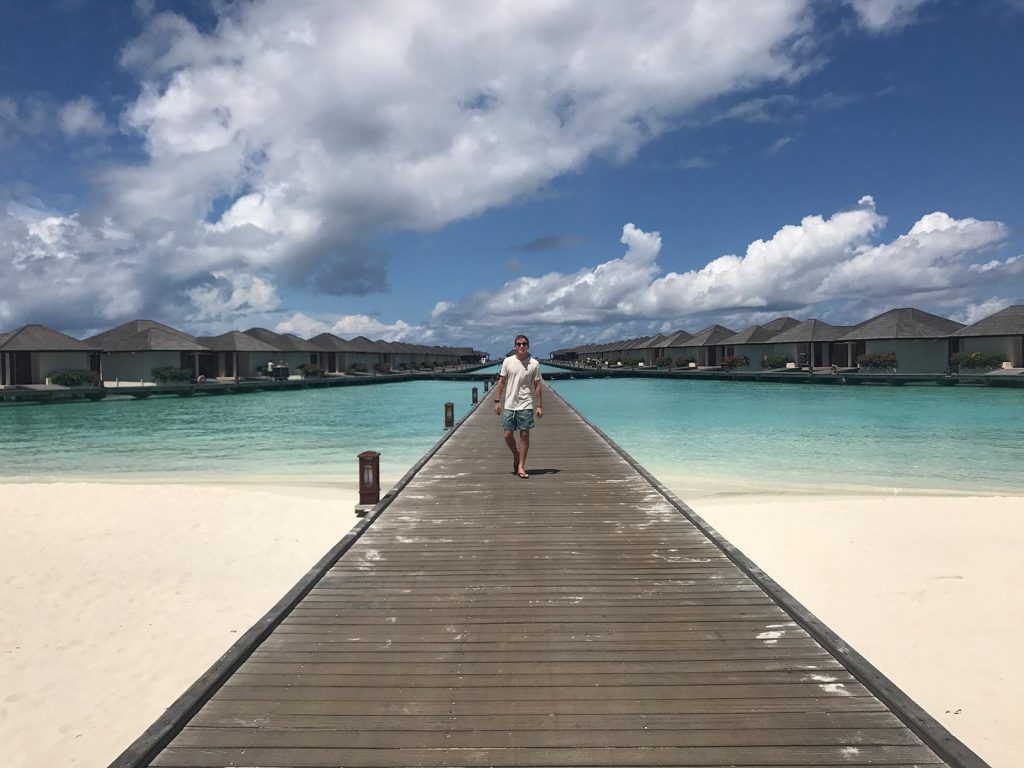 David Simpson walking the walkway to shore from water villa in Maldives. The Maldives & upgraded to the best villa on the island