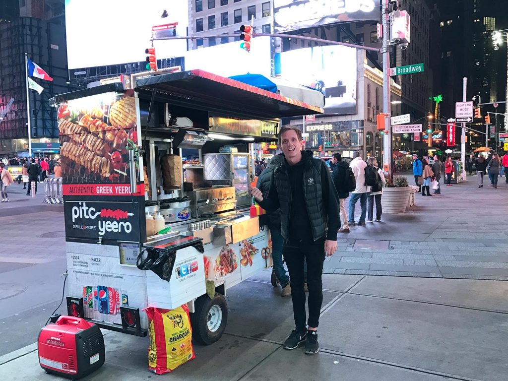 David Simpson with street food cart at night in New York City, USA. A missed flight to New York
