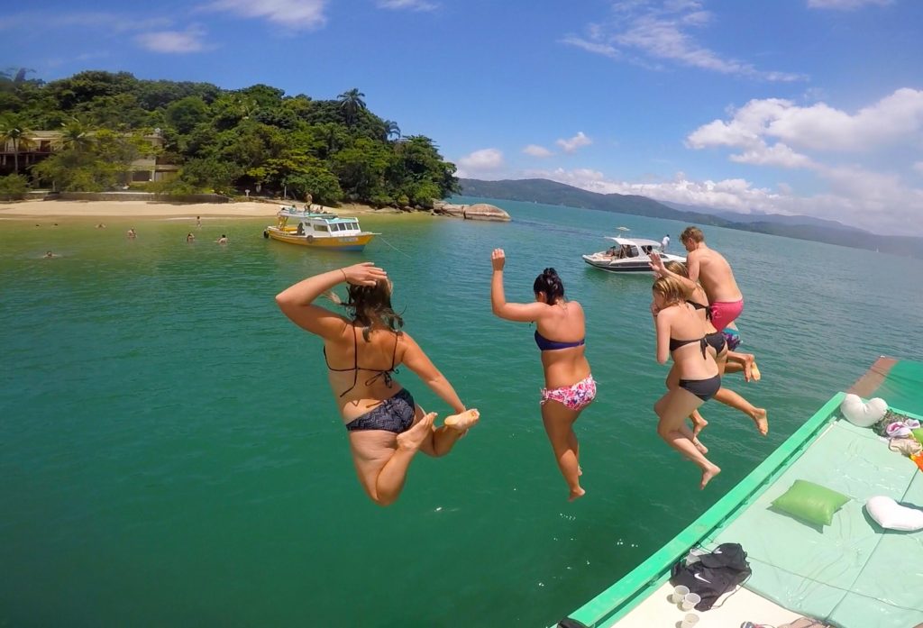 Friends diving into the water from the party boat in Paraty, Brazil. Rockfalls, Paraty boat party and nearly losing my head