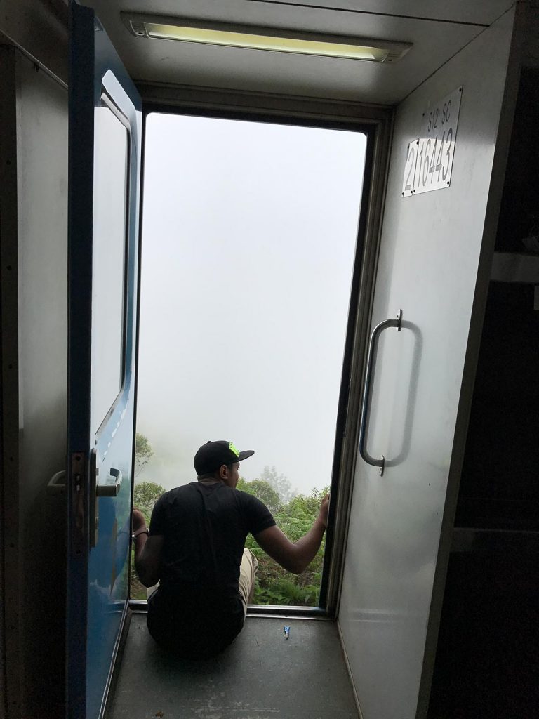 Guy enjoying the view at door of train in Ella, Sri Lanka. The Train Ride of a Lifetime pt2, Ella