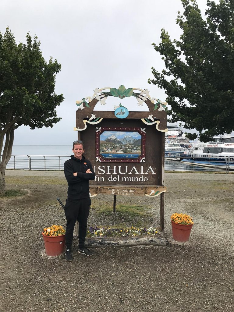David Simpson standing near sign in Ushuaia, Argentina. Cape Horn on the Cruise to the end of the world