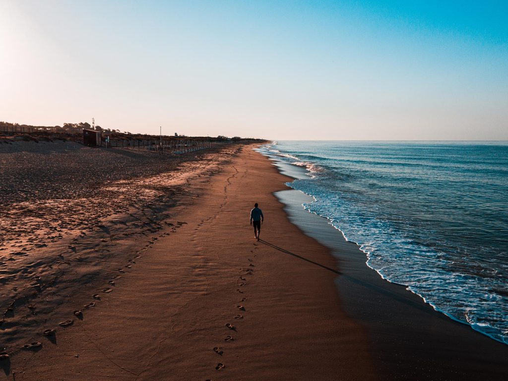 DAVID SIMPSON WALKING DOWN A QUIET BEACH IN PORTUGAL ALONE AT SUNRISE
