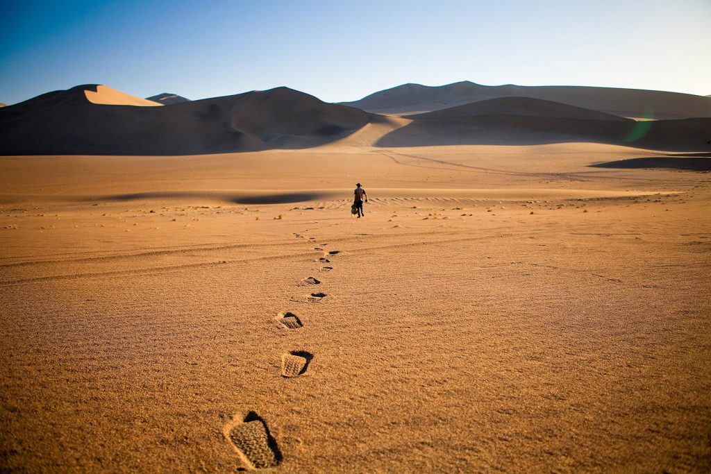 Man walking along in the desert on a sunny day. Scared of travelling alone?