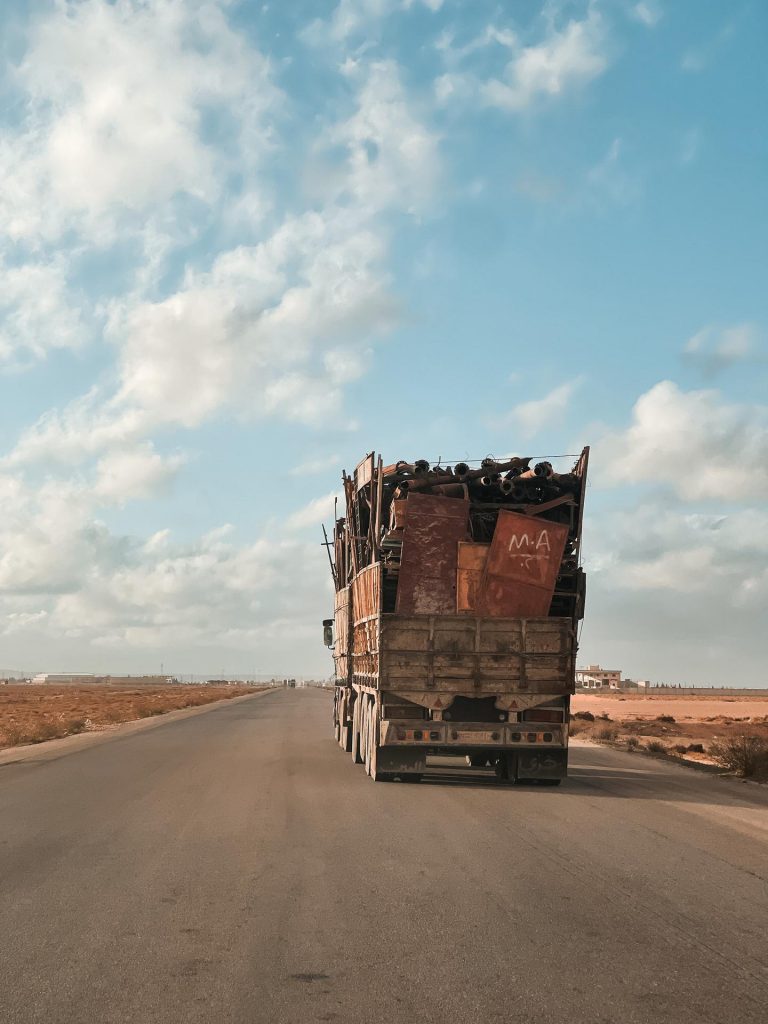 Truck full of scrap metal driving on the highway in Palmyra, Syria. The ruined ruins of Palmyra