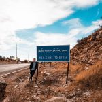 David Simpson standing by a bullet riddled Lebanon, Syria border sign. Where have I been so far