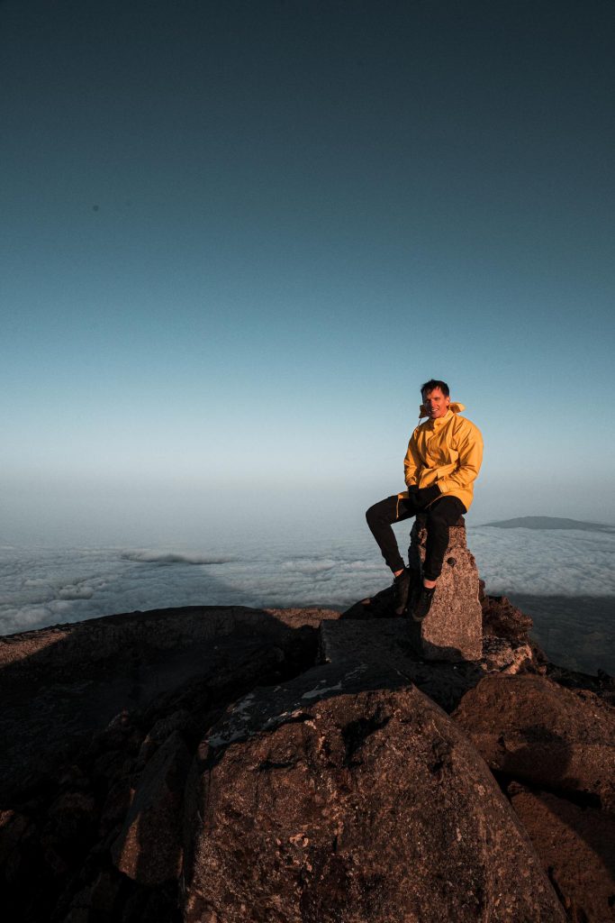 David Simpson sitting at summit of Pico, The Azores. Camping in volcano Pico, Portugal’s highest mountain