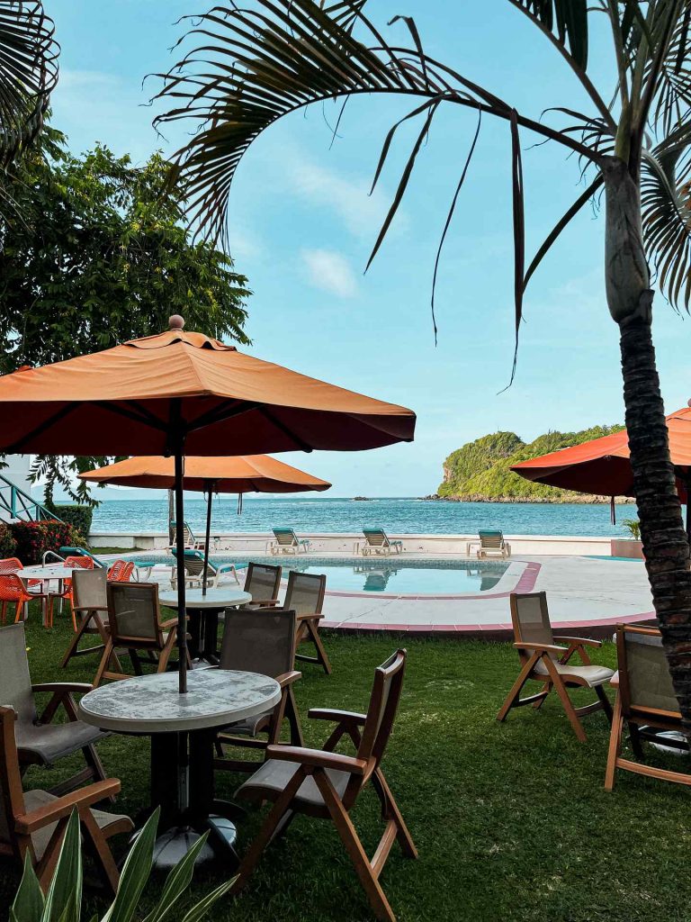 Trees and poolside tables, chairs and umbrellas by the sea in Saint Vincent and the Grenadines. Quarantine detour!
