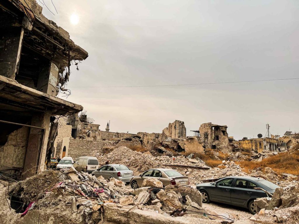 Cars parked near war damaged buildings in Aleppo. A day in Aleppo and generosity of new friends
