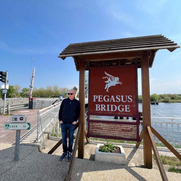 Dad standing by sign in Pegasus Bridge in Normandy, France. The best viewpoint, museum and cafe in France
