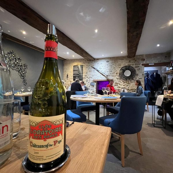 Bottle of wine and diners in La Rapiere Restaurant in Bayeux in Normandy, France. The best steak & omelette in the world in the same day