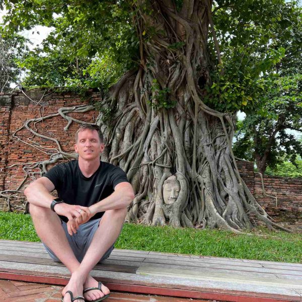 David Simpson by a Buddha Head in the roots of a tree in Ayutthaya, Thailand. Ayutthaya, food frenzy & cryo time