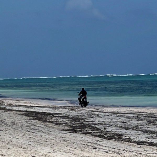Man riding motorcycle by the beach at The Rock Restaurant in Zanzibar, Tanzania. Worst food with the best view at the Rock, Zanzibar