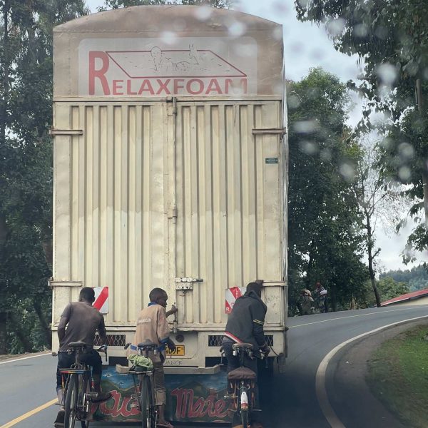 Bikers holding on to truck along the highway in Musanze, Rwanda. Climbing Mt Bisoke