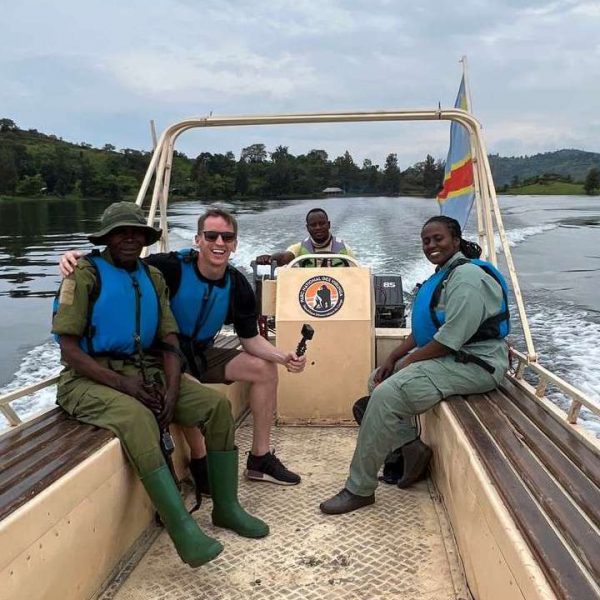 David Simpson and rangers onboard a boat in Musanze, Rwanda. Climbing Mt Bisoke