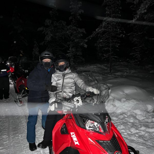 Mom and dad by the snow mobile at night in Ivalo, Finland. The truth about Kakslauttanen Arctic resort