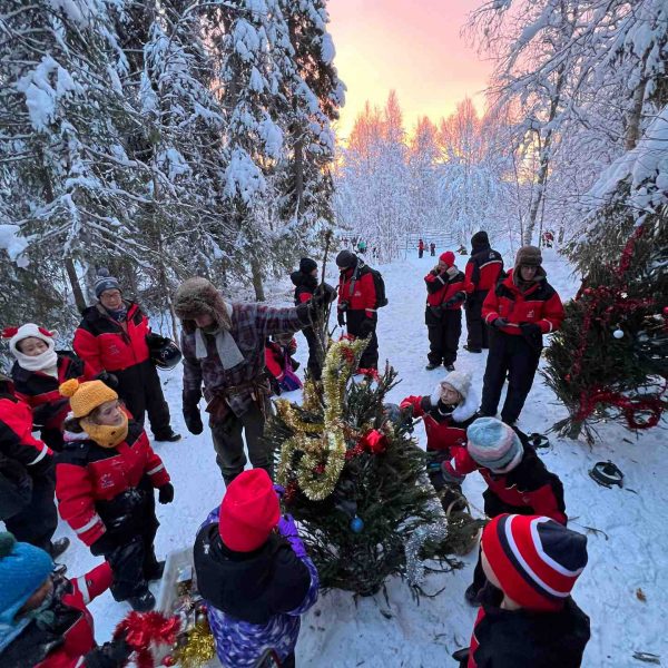 People watching the sunrise by the woods in Rovaniemi, Finland. Christmas Day in Lapland